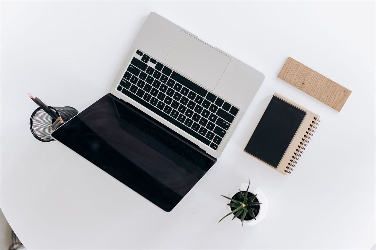 An open laptop and notebook on a light desk