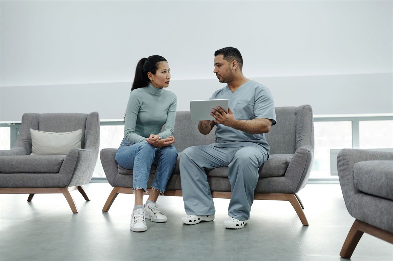A clinician talking with a patient while holding a tablet